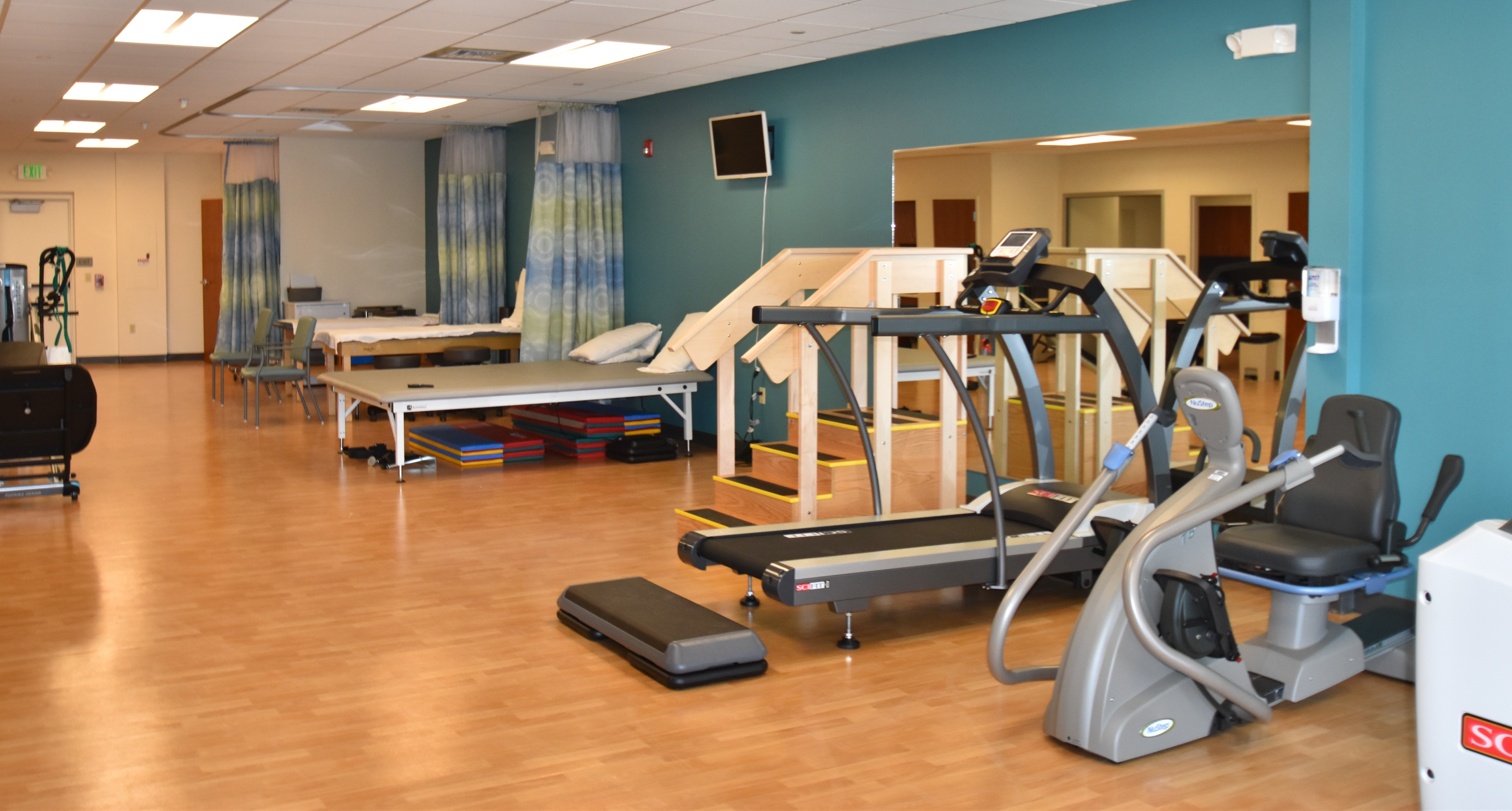 A rehab center built by Ondra-Huyett that has a teal wall, treadmill, exercise bike and patient bed.